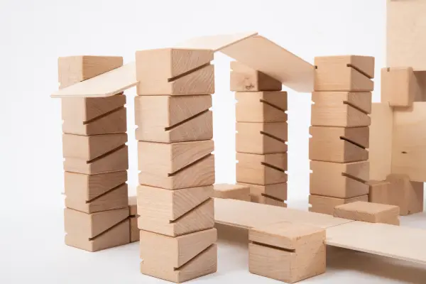 The boy is playing with wooden building blocks.