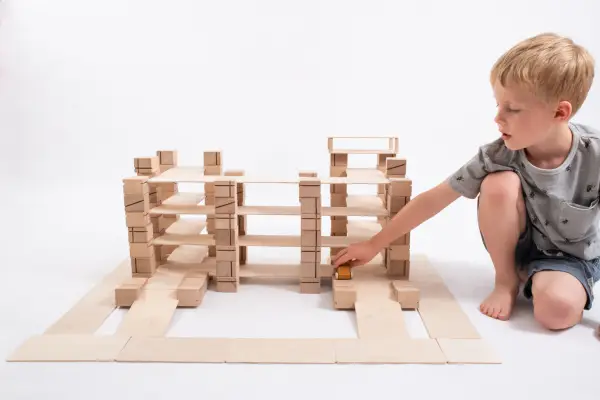 Wooden parking lot for toy cars and the boy playing blocks.